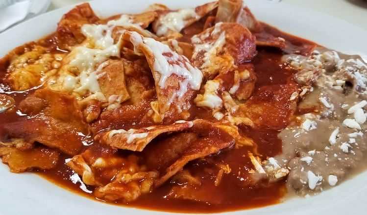 sauce and cheese slathered over a dish next to refried beans